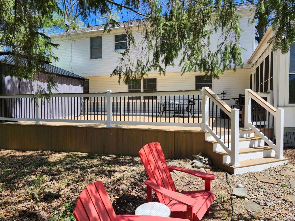 Backyard composite deck with white posts, black balusters, and wide steps for patio dining