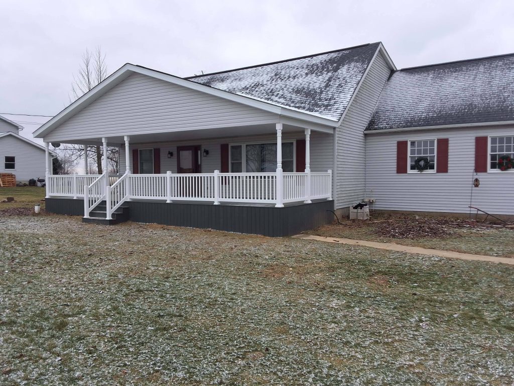 Finished covered front porch with gable roof and white vinyl railings on ranch home