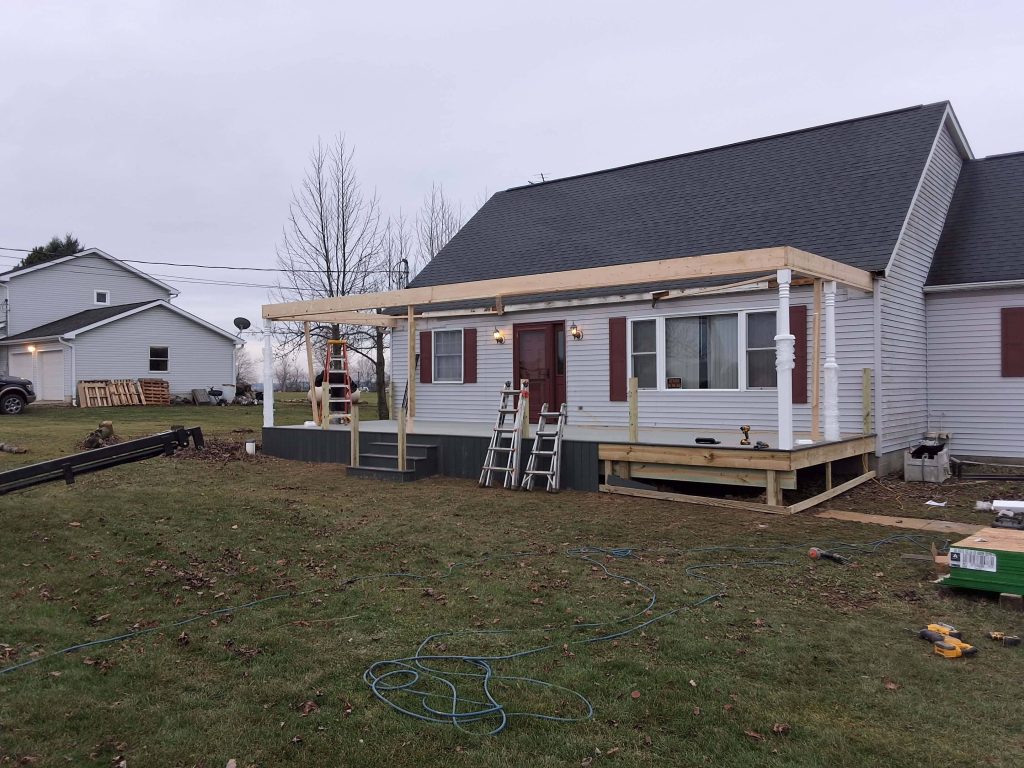 Front-porch addition framing with posts and beams on ranch house—new covered entry build