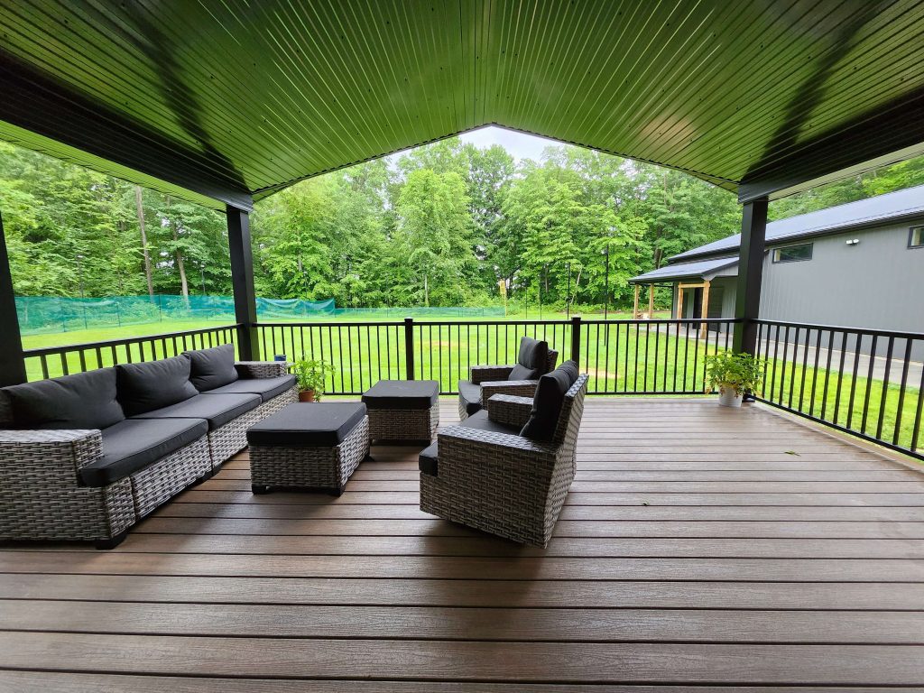 Covered composite porch with wicker seating overlooking lawn, completed by D Miller Exteriors Apple Creek OH