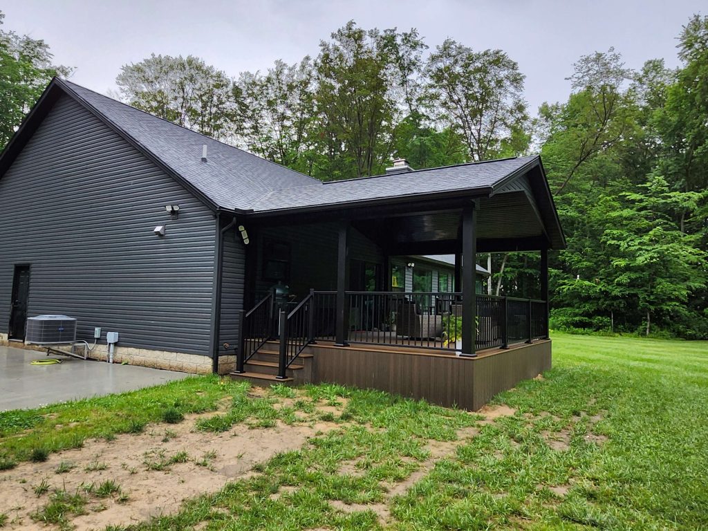 Exterior view showing charcoal siding home and new covered porch with black rail built by D Miller Exteriors Apple Creek OH