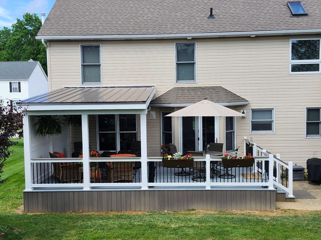 Finished composite deck and screened roof addition with white rails and flower planters built by D Miller Exteriors Apple Creek OH